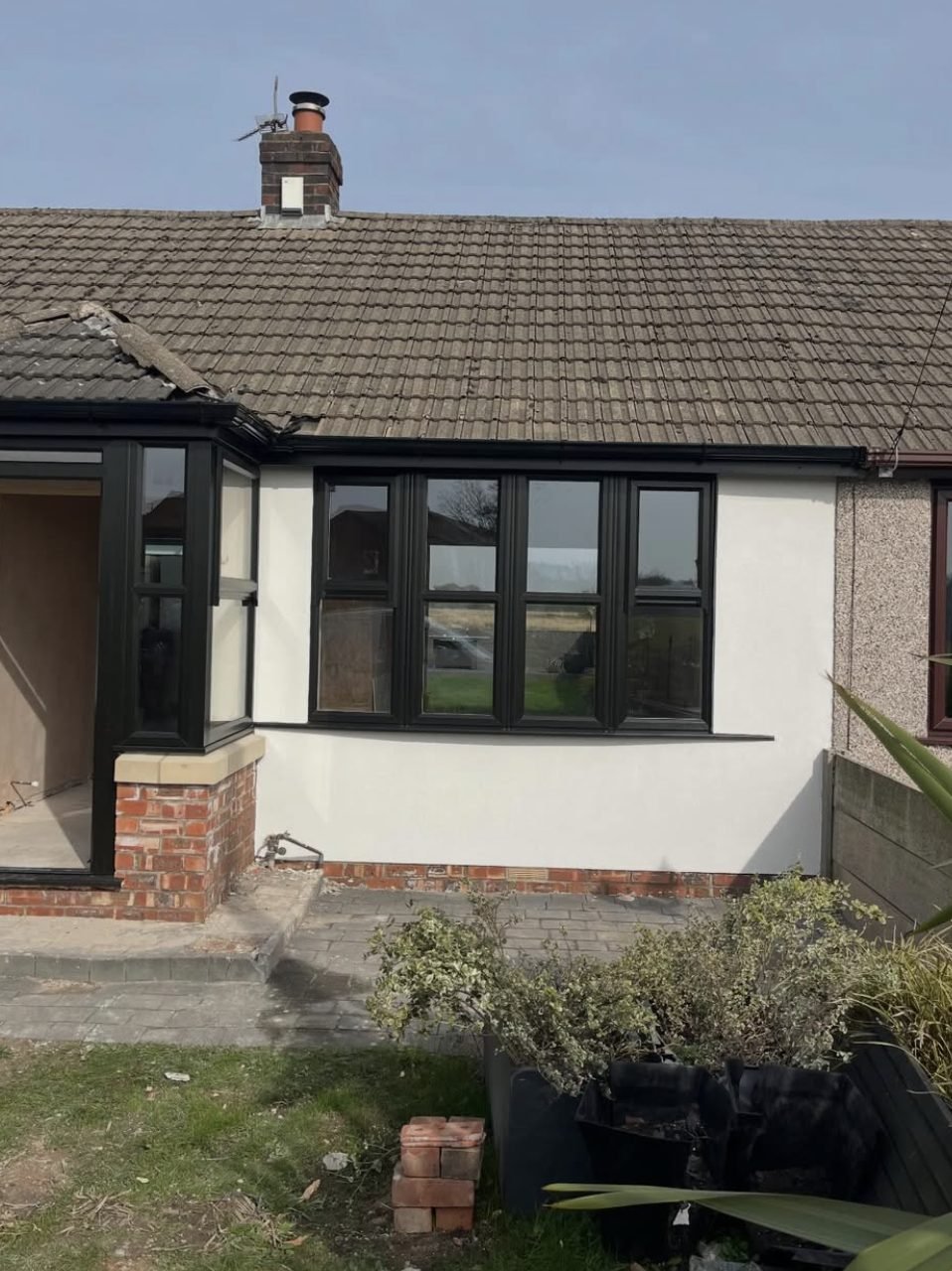 Bungalow front in a smooth white finish beside a neighbour's pebbledashed wall