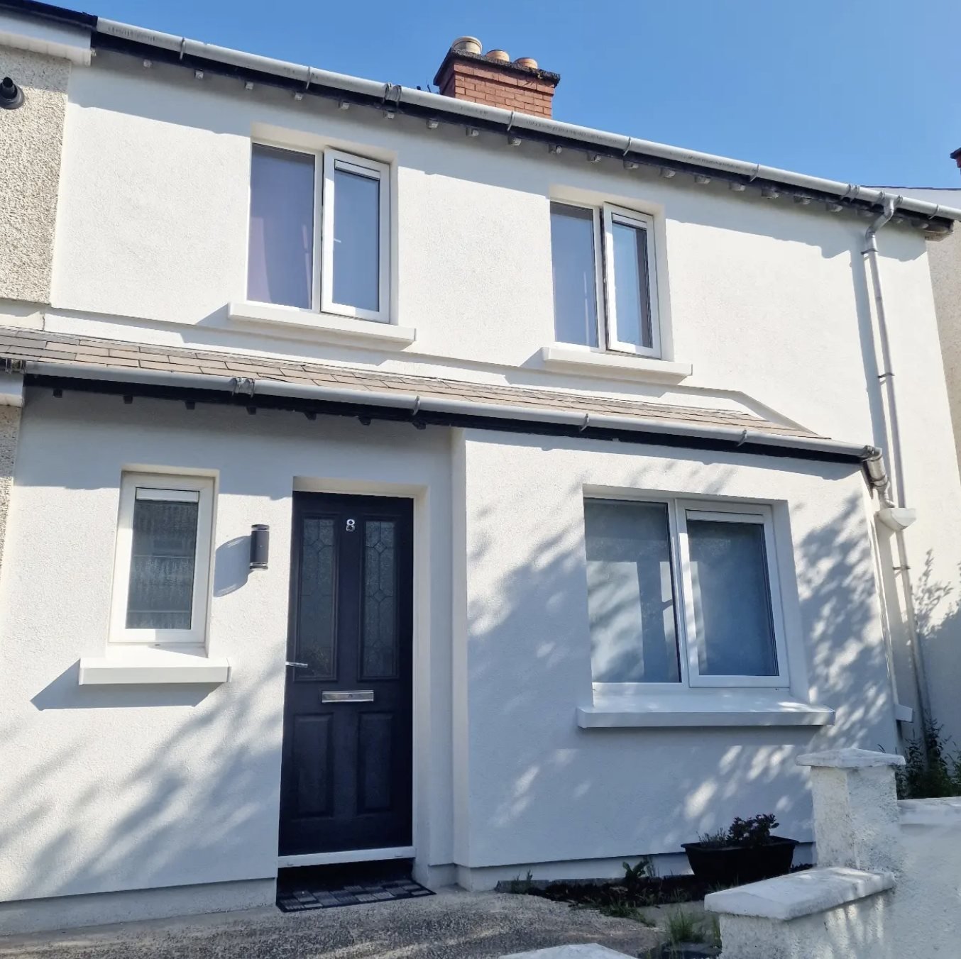 Terraced house finished in white with deep window sills and a black door